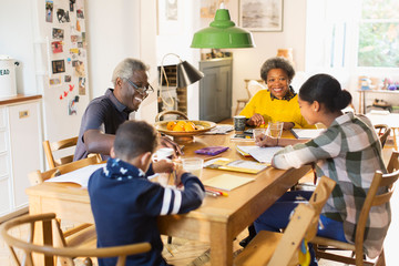 Grandparents at dining table with grandchildren doing homework