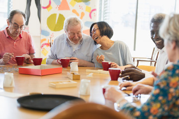 Happy senior friends playing games at table in community center