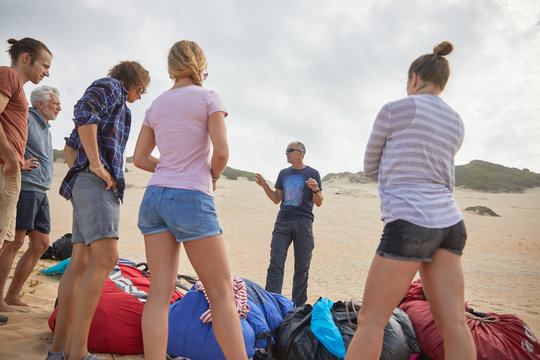 Male paragliding instructor talking to students on beach