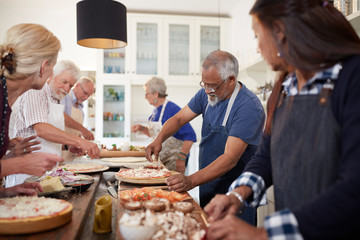Senior friends making pizzas in cooking class