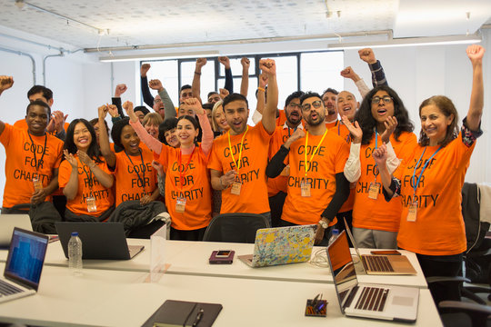 Portrait confident hackers cheering, coding for charity at hackathon