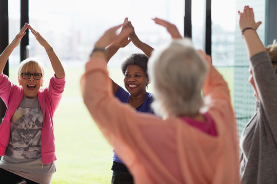 Happy active senior women exercising, stretching arms overhead in exercise class - Powered by Adobe