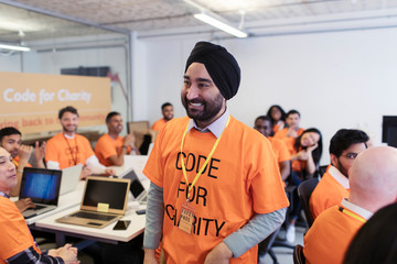 Happy, confident hacker in turban coding for charity at hackathon
