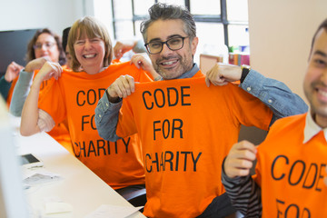 Portrait confident hackers in t-shirts coding for charity at hackathon