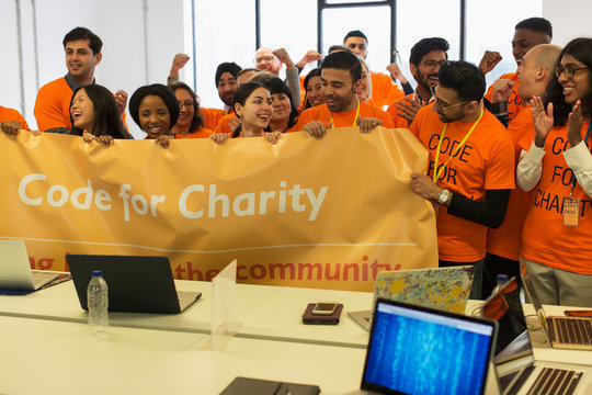 Hackers with banner cheering, coding for charity at hackathon