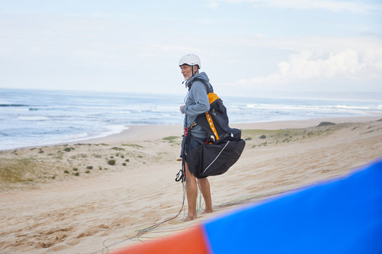 Paraglider with parachute backpack on ocean beach