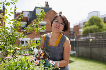 Portrait smiling woman gardening in sunny yard