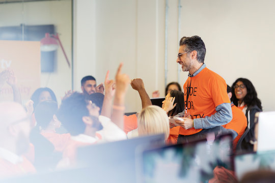 Man leading cheering hackers coding for charity at hackathon