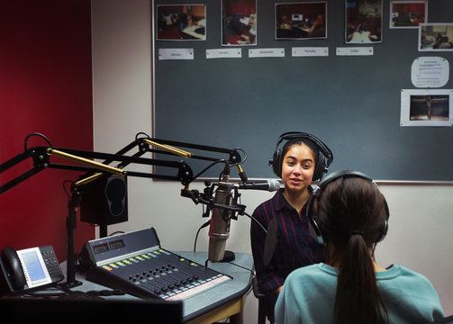 Teenage girl musicians recording music, singing in sound booth