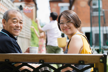 Portrait smiling daughter senior father drinking tea on bench in yard