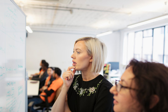 Focused businesswomen brainstorming at whiteboard in office
