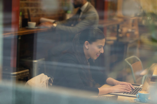 Smiling businesswoman working at laptop in cafe