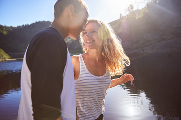 Affectionate, carefree couple at sunny summer lake