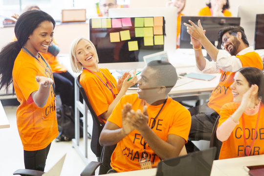 Enthusiastic hackers cheering, coding for charity at hackathon