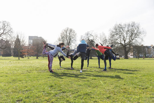 People exercising, stretching in sunny park