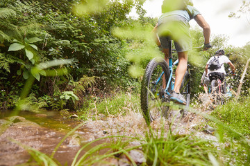 Man mountain biking, splashing on muddy trail