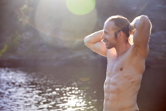 Carefree bare chested man at sunny summer lake