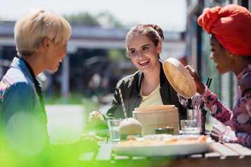 Young women friends eating dim sum lunch at sunny sidewalk cafe