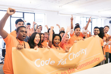 Portrait enthusiastic hackers cheering banner, coding for charity at hackathon