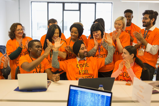 Enthusiastic hackers celebrating, coding for charity at hackathon