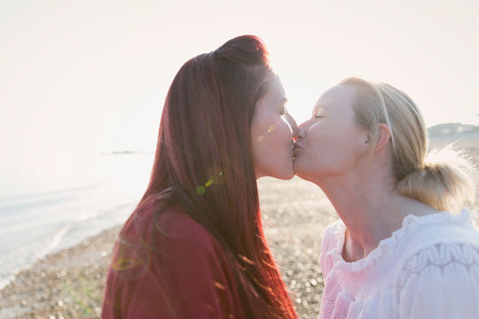 Affectionate lesbian couple kissing on sunny beach