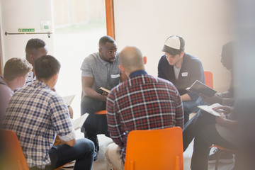 Men reading and discussing bible in circle in prayer group
