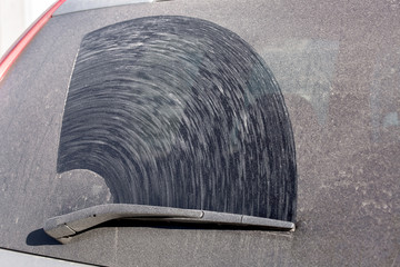 hatchback back window of a dirty car in a layer of dust and dry dirt, close up of a dirty vehicle...