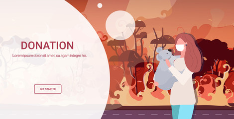 woman in mask holding koala bear forest fires animals dying in wildfire bushfire natural disaster pray for Australia donation concept intense orange flames horizontal portrait copy space vector © mast3r