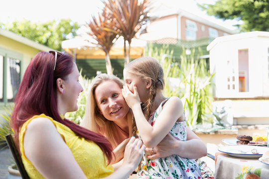 Affectionate lesbian couple holding daughter on sunny patio