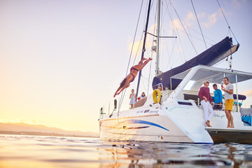 Young woman diving off catamaran into ocean