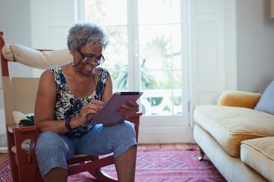Senior woman using digital tablet in living room - Powered by Adobe