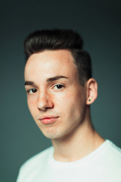 Portrait confident teenage boy with freckles and earring