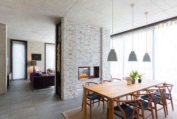 Pendant lights over dining table in modern dining room with fireplace