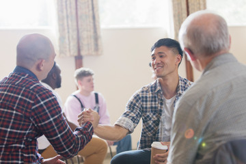 Men shaking hands in group therapy in community center
