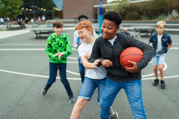 Tween boys playing basketball in schoolyard