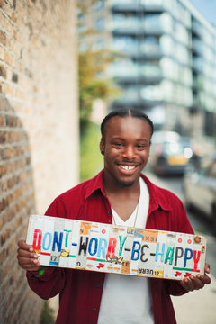 Portrait smiling teenage boy holding Dont Worry Be Happy license plates