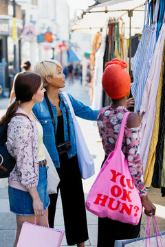 Young women friends shopping on urban sidewalk