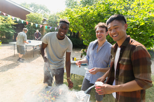 Portrait smiling male friends enjoying summer backyard barbecue