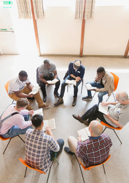 Men reading and discussing bible in prayer group
