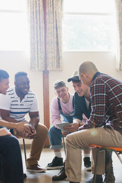 Men with digital tablet talking in group therapy circle