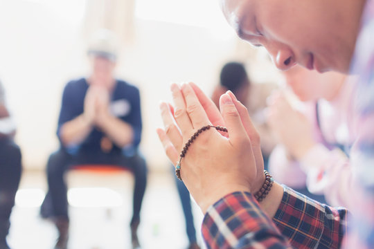 Man praying with prayer beads in prayer group