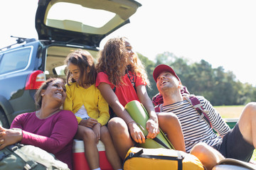 Happy family with camping equipment at back of car