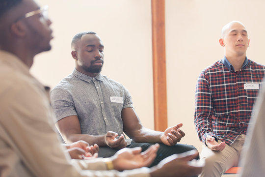 Men praying with eyes closed in prayer group