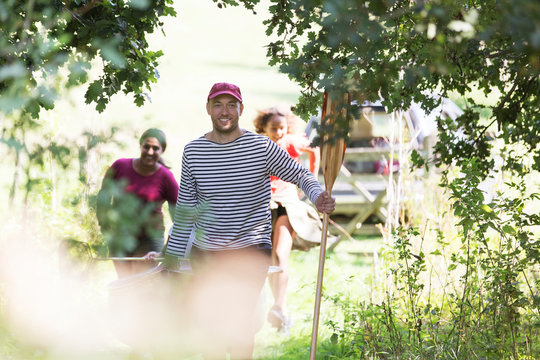 Family carrying canoe in woods