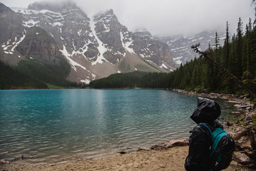 Serene hiker in rain jacket enjoying tranquil mountain lake view, Banff, Alberta, Canada