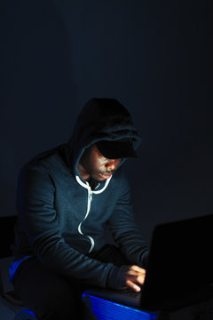 Teenage boy in hoody sitting at laptop