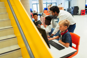 Teacher helping junior high students using computers in library