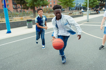 Tween boys playing basketball in schoolyard