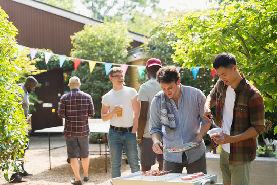 Male friends enjoying barbecue in sunny backyard