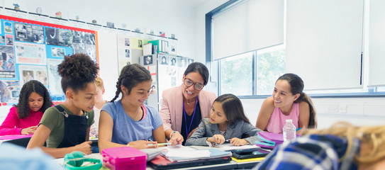 Female teacher junior high school girl students at desk in classroom